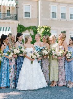 a group of women standing next to each other in front of a building with flowers