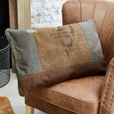 a brown chair sitting in front of a window with a pillow on top of it