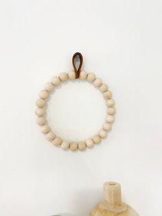 a wooden beaded bracelet hangs on the wall next to two vases and a bottle