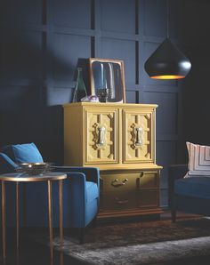 a living room with blue couches and a gold cabinet in the corner next to a chair