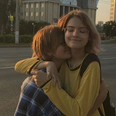 two people hugging each other on the street