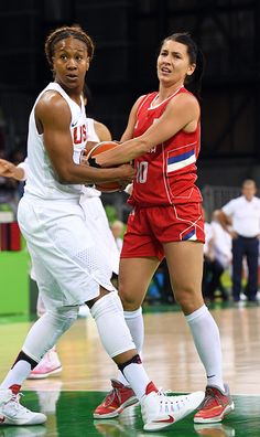 two women in uniforms playing basketball on a court