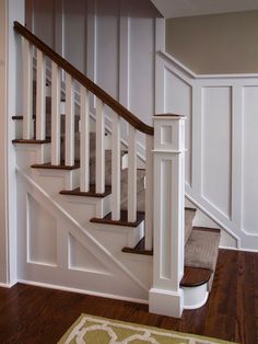 a white staircase with wooden handrails and carpeted flooring in a home