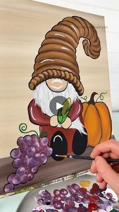 a person is painting an image with acrylic paint on a canvas and some grapes