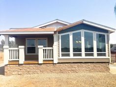 a small house with windows on the front and side of it, sitting in an empty lot