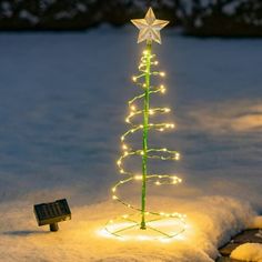 a lighted christmas tree in the snow with a star on it's top,