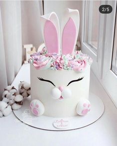 a white cake decorated with pink flowers and bunny ears