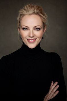 a woman with her arms crossed smiling at the camera