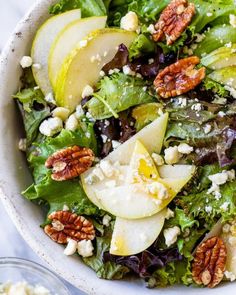 a salad with apples, walnuts, and feta cheese in a white bowl