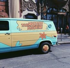 the mystery machine van is parked on the side of the street in front of a building