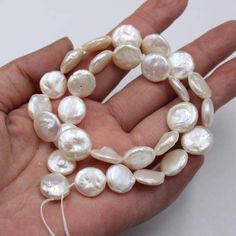 a hand holding a strand of white pearls