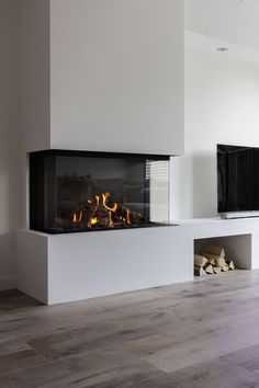 a modern fireplace in a living room with white walls and wood flooring, along with a flat screen tv mounted on the wall