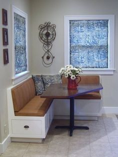 a corner table with a bench in front of it and a vase on the side