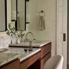 a bathroom with marble counter tops and two sinks in front of large mirrors on the wall