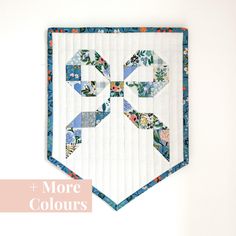 a quilted wall hanging with the words more colours written in white and blue on it