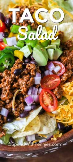 taco salad in a bowl with lettuce, tomatoes, black olives and cheese