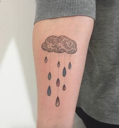 a woman's arm with a cloud and raindrops tattoo on the left forearm