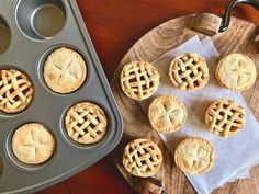 mini pies sitting on top of a wooden tray next to a muffin tin