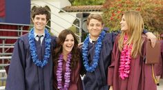 a group of young people standing next to each other wearing graduation gowns and leis