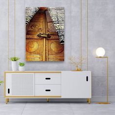 an abstract painting on the wall above a cabinet in a room with white walls and flooring