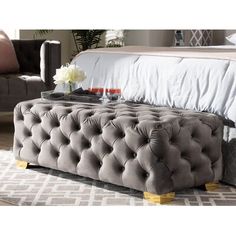 a large gray tufted bed sitting on top of a wooden floor