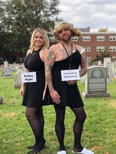 two people standing next to each other in front of tombstones with signs on them