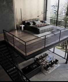 a bed sitting on top of a wooden floor next to a metal stair case in a living room