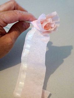 someone is holding a piece of tissue paper with a flower on it, and they are cutting out the fabric