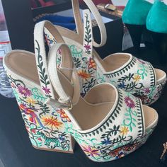 a pair of white high heels with colorful flowers on them