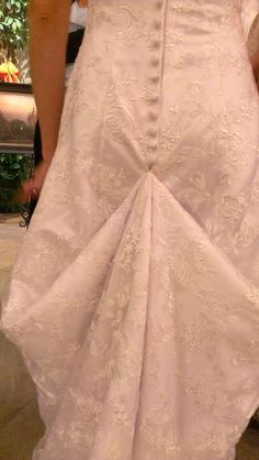 the back of a woman's wedding dress, with her hands on her hips