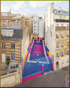 an aerial view of a basketball court in the middle of some buildings with graffiti painted on it