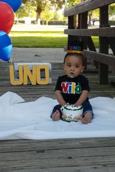 a little boy sitting on top of a blanket next to a cake