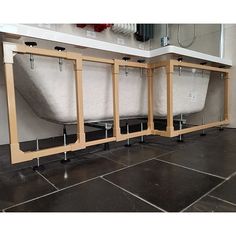 three wooden benches sitting on top of a black tile floor next to a wall with mirrors above them