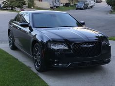 a black car parked on the side of a road next to a street with houses in the background