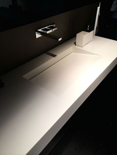 a bathroom sink with two faucets on it's sides and a tissue dispenser next to it