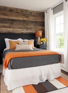 a bedroom with wood paneling and white curtains on the window sill, along with a large bed