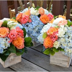 two wooden boxes filled with colorful flowers on top of a wooden table next to each other