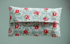 a white and red flowered pillow hanging from a hook on a wall in a room