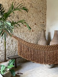 a hammock hanging from the side of a wall next to a potted plant