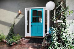 a blue front door on a house with plants and potted plants in the foreground