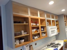 a kitchen with wooden cabinets and white microwave above the stove top, along with other appliances