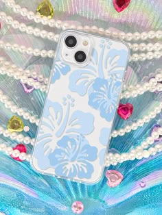 an iphone case with blue flowers and pearls on the bottom, surrounded by other beads