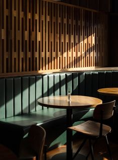 two tables and chairs in a room with wood paneling on the wall behind them