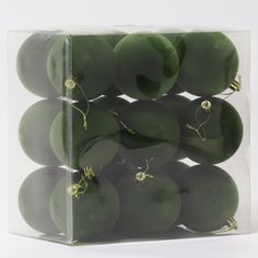 a clear box filled with green vegetables on top of a white table next to a wall