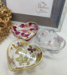 three heart shaped dishes sitting on top of a table next to a vase and flowers