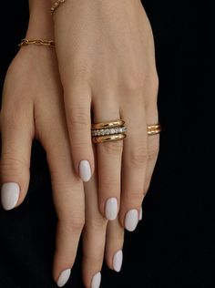 a woman's hand with three different rings on her fingers and two gold bracelets