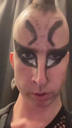 a woman with black and white makeup has her face painted like a cat's head