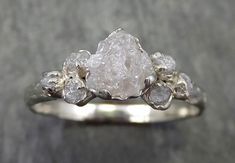 a white diamond ring sitting on top of a gray surface with three diamonds around it