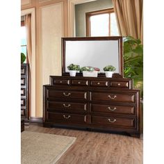 a bedroom scene with focus on the dresser and large mirror in the middle, along with an area rug