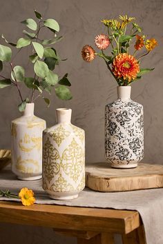 three vases with flowers in them sitting on a table